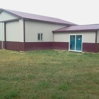 Metal building with burgundy trim and lawn.